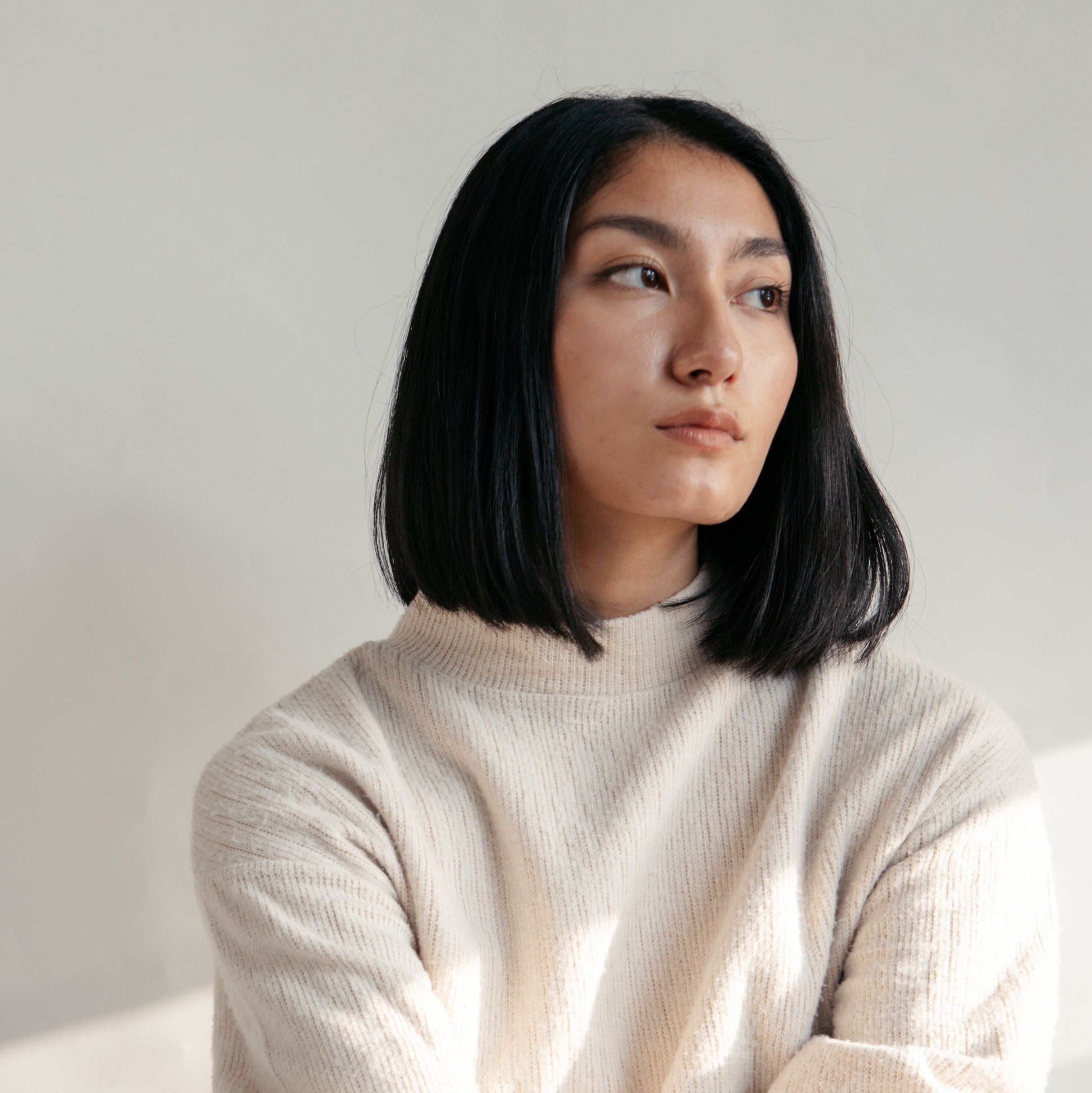 Woman wearing a beige sweater against a plain background